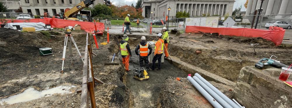 Workers stand in a construction site discussing their next task