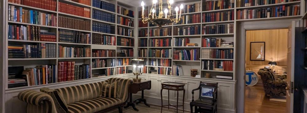 A picture of the library in the Governor's mansion that shows shelves lined with books and a chandelier hanging from the ceiling