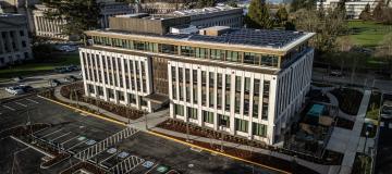 A bird's eye view of the Irving R. Newhouse Building, showing the new structure and parking lot, with the West Campus lawns and Capitol Group buildings visible in the background.